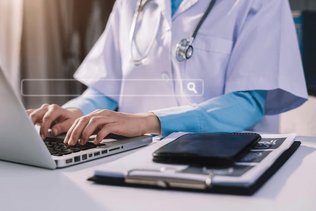 A doctor typing on a laptop, focused on their work in a clinical setting.