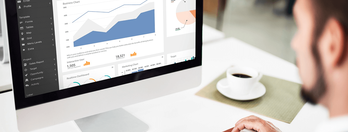 A man analyzes graphs displayed on his computer screen, focused on data interpretation