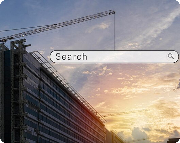 A construction worker wearing a yellow hard hat and safety vest is using a laptop at a construction site, with cranes and buildings in the background, symbolizing the integration of technology in construction.