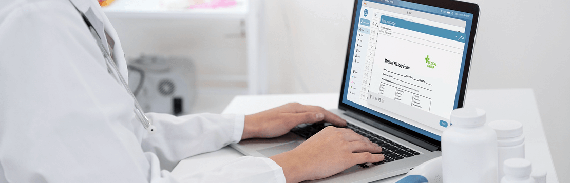 A person typing on a laptop while wearing a stethoscope, suggesting a connection between technology and healthcare.